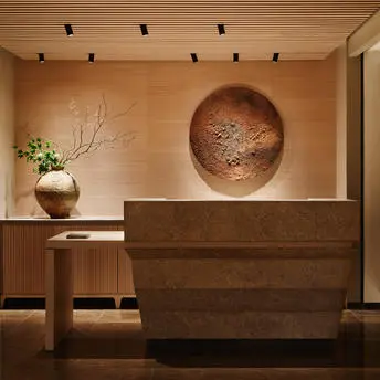 Réception du spa Aman New York, avec comptoir en bois sombre et art mural minimaliste.