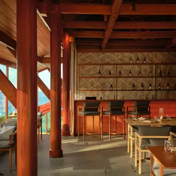 Dining space at Amanpuri featuring a sake bar with wooden beams, red walls, and traditional Japanese seating.