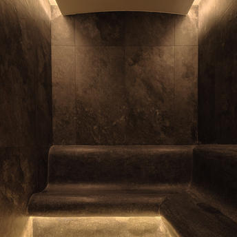 Wellness steam room at Amanpuri resort, with dark stone walls and warm ambient lighting.