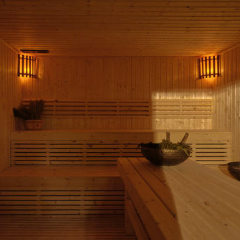 Traditionelle Holzsauna mit Bänken und warmer Beleuchtung in der Spa-Anlage des Amanpuri Resorts in Thailand.