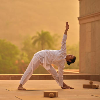 Guest practising yoga on a terrace at Amanbagh, India, at sunrise.