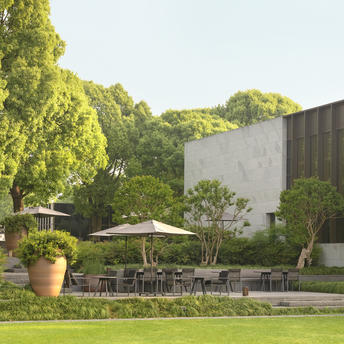 Outdoor seating area at Amanyangyun with terracotta urns, manicured lawn and contemporary architecture.