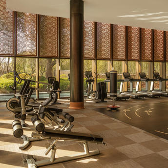 Wellness studio at Amanyangyun with exercise equipment, natural light from latticed windows, and wooden wall panels.