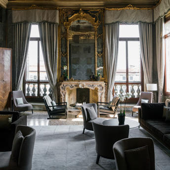 Salle Tiepolo ornée de fresques dorées, mobilier noir et fenêtres hautes à Aman Venice.