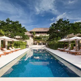 Rectangular swimming pool with loungers and white parasols at Aman Villas at Nusa Dua, Bali.