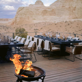 Outdoor terrace at Amangiri resort with fire pit, seating and desert rock formations at dusk.