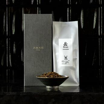 Black bean roasted tea in branded packaging at Aman Kyoto, displayed with bowl and grey box.