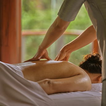 Massage therapist's hands performing treatment on guest's leg at Amanpuri resort spa.