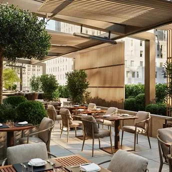 Terrasse de jardin ombragée à Aman New York, avec mobilier de détente et plantes verdoyantes.