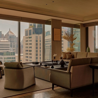 Aman Suite at Aman Nai Lert Bangkok with city views from floor-to-ceiling windows, warm furnishings and contemporary décor.