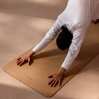 Person in white clothing performing a yoga pose on a cork mat at Amanbagh.