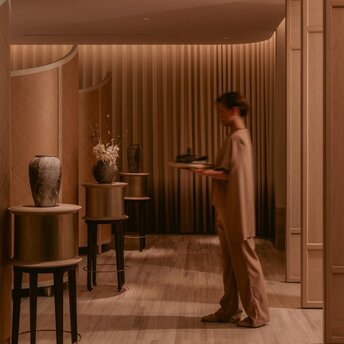 Spa treatment room at Aman Nai Lert Bangkok with warm wooden interiors and sculpted wellness decor.