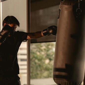 Boxer training on heavy bag at Aman Nai Lert Bangkok's gym facility.