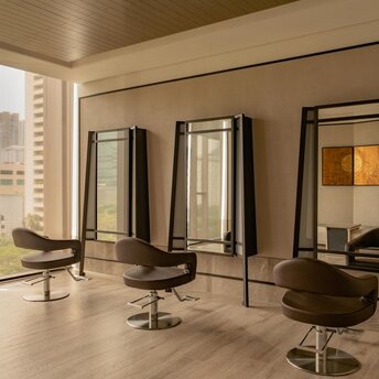 Salon styling stations with mirrors and chairs at Aman Nai Lert Bangkok spa and wellness facility.