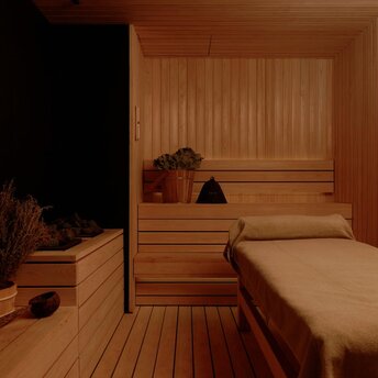 Wooden sauna interior at Aman Nai Lert Bangkok with bench seating and warm lighting.