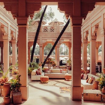 Terracotta courtyard at Amanbagh with red pillars framing views of seated areas and potted plants.