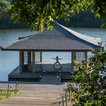Lakeside spa pavilion at Amanoi with a figure on the wooden platform overlooking lotus waters in Vietnam.