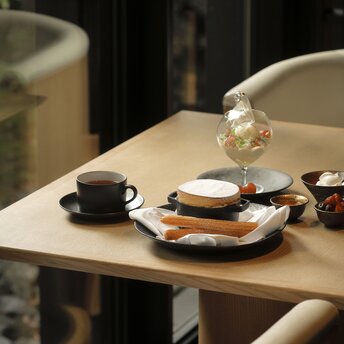 Cheese soufflé served on a plate at Aman Kyoto, with tea and pastries on a dining table.