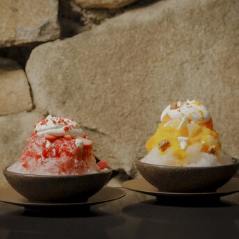 安缦东京酒店咖啡馆中，两碗刨冰甜品，一碗覆盖红色糖浆，另一碗覆盖黄色糖浆。