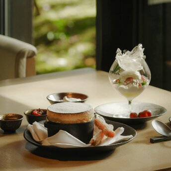 Cheese soufflé served on a plate at Aman Kyoto resort, with tea cup and pastries on a pale table.
