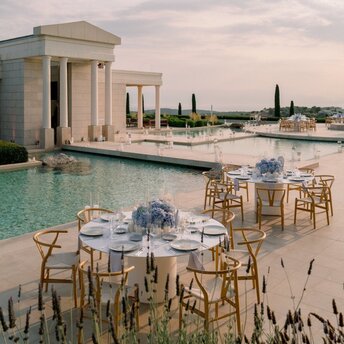 Tableaux dressées pour un mariage au bord de la piscine à Amanzoe, en Grèce, avec vue sur la baie.