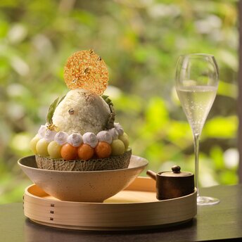 Aman Kyoto resort's melon shaved ice dessert with layered fruit and delicate garnish on wooden plate.