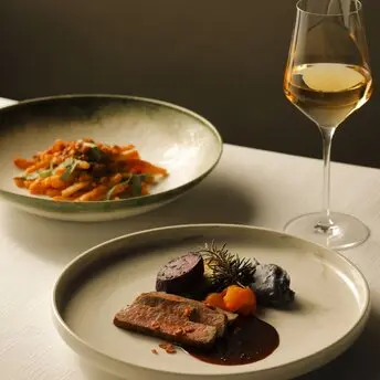 アマン東京のヌチグスイ料理店で、白ワインと共に提供される2皿の洗練された料理。