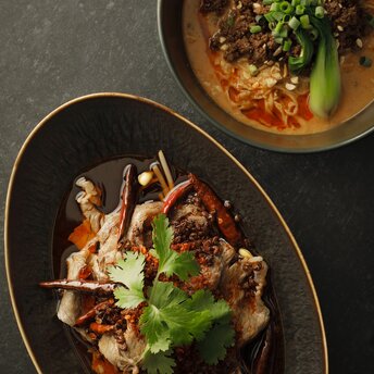 アマン東京のラウンジで提供される中華料理。金縁の黒い皿に盛られた肉料理と野菜。