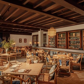 Amanfayun library lounge with wooden beams, bookshelves, and woven chairs arranged around tables.