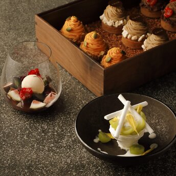 Plated desserts and pastries displayed at Aman Tokyo café, featuring delicate confections in a wooden box and on ceramic plates.