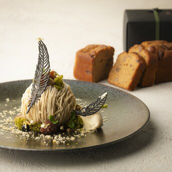 Plated fish dish with microgreens at Aman Kyoto, freshly baked bread visible in background.