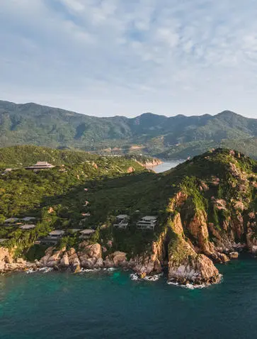 Amanoi accommodation perched on a clifftop overlooking turquoise waters and forested mountains in Vietnam.