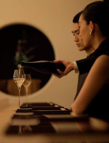 A guest enjoys an intimate dining moment at Aman Tokyo, with candlelight and a glass of wine.