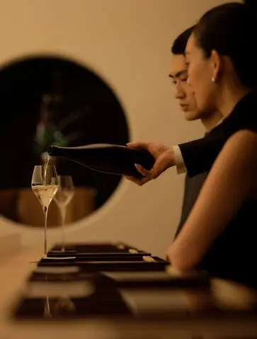 A guest enjoys an intimate dining moment at Aman Tokyo, with candlelight and a glass of wine.