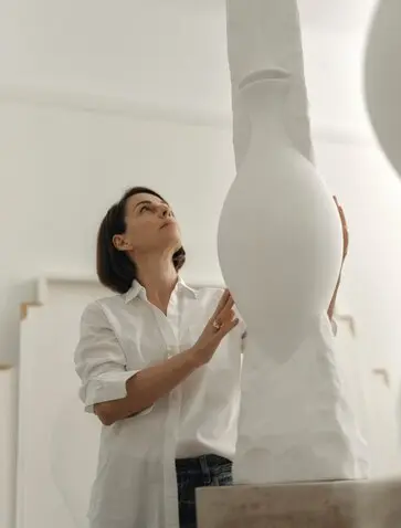 Studio portrait of artist Nikomachi Karakostanoglou beside sculptural artwork at Amanzoe, Greece.