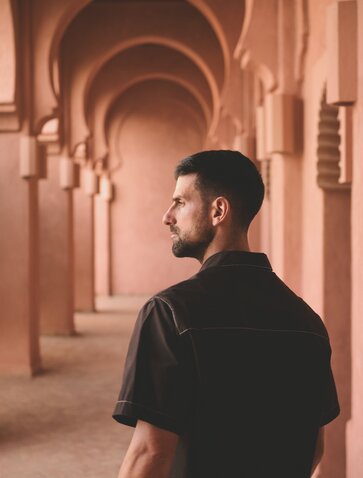 Novak Djokovic walking through a terracotta-coloured arched corridor at Amanjena, Morocco.